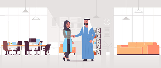 arabic businesspeople man woman handshaking arab business partners couple hand shake during meeting agreement partnership concept modern co-working center office interior full length horizontal