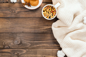 Autumn or winter composition. Cup of herbal tea, women fashion white sweater, cotton on wooden background. Flat lay, top view, copy space. Cozy home desk, hygge, autumn fall concept