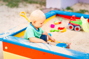 Cute baby boy playing in the sandbox