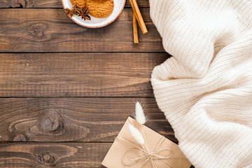 Autumn or winter flatlay composition with white wool plaid, crft paper envelope, cinnamon sticks, cookies, dry flowers. Cozy home desk, hygge concept. Flat lay, top view, overhead.