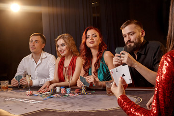 Group of a young wealthy friends are playing poker at a casino.