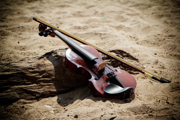 The wooden violin and bow put beside timber board,on the beach,blurry light around