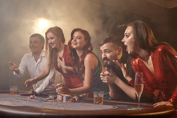 Group of a young wealthy friends are playing poker at a casino.