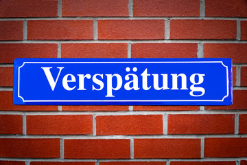 Verspätung Schild blau an Backsteinwand