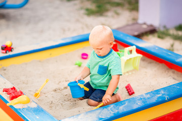 Cute baby boy playing in the sandbox