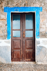 Old brown wooden entrance door with windows of a vintage stone house in Bodrum, Turkey.