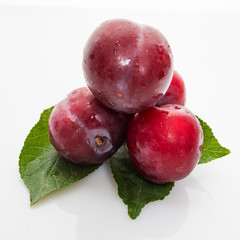 Obraz premium red plum with green leaves isolated on white background