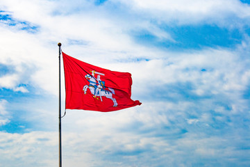 Historical Lithuanian flag, coat of arms of Lithuania, consisting of an armour-clad knight on horseback holding a sword and shield, is also known as Vytis, waving in the wind against cloudy sky 