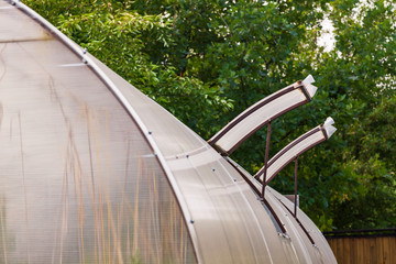 Close-up on open windows in a greenhouse constructed of polycarbonate and plastic for ventilation of hot air and the cultivation of vegetables and fruits. Agriculture and farming.