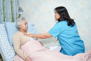 Obraz premium Asian nurse physiotherapist doctor care, help and support senior or elderly old lady woman patient lie down in bed at hospital ward : healthy strong medical concept.