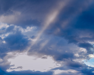 Sunbeams radiating out under colorful clouds during a sunset.