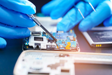 Asian Technician repairing micro circuit main board of smartphone electronic technology : computer,...