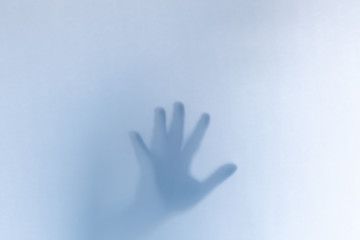 Defocused scary ghost hands behind a white glass background