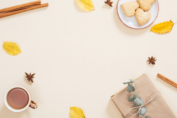 Fototapeta na wymiar Pattern made of dry autumn leaves, gift box, cookies, cup of tea, cinnamon sticks. Fall flat lay. Top view. Autumn minimal concept