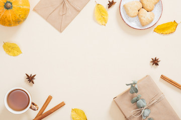 Frame made of dry autumn leaves, pumpkin, gift box, envelope, cookies, cup of tea, cinnamon sticks. Fall flat lay. Top view. Autumn minimal concept