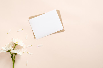 Daisy flowers and letter with blank paper card mockup on pastel pink background. Flat lay, top view, overhead. Romance and love at distance concept.