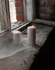 Two burning candles in the old window on the background of the cobweb