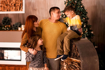 Portrait of a happy young family with two children on the background of the Christmas tree at home..