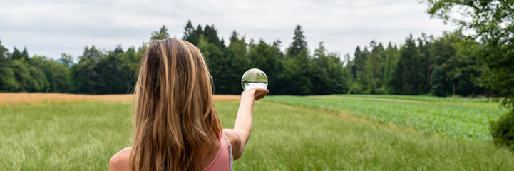 Woman standing in nature holding crystal ball - Powered by Adobe