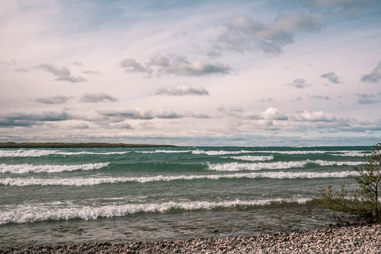 White cap waves rolling into shore under dynamic clouds