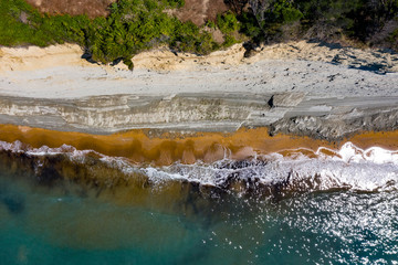 Aerial view of beautiflul rocky cliff and sandy beach by the ocean.