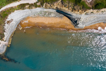 Aerial view of beautiflul rocky cliff and sandy beach by the ocean.