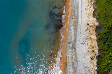 Aerial view of beautiflul rocky cliff and sandy beach by the ocean.