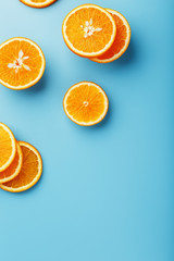 Round slices of juicy orange on a blue background, top view as a background substrate. Food background