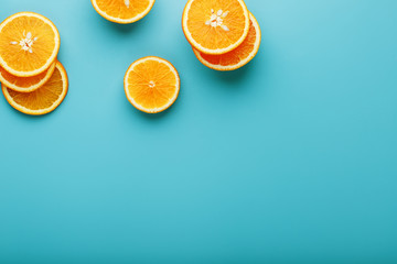 Round slices of juicy orange on a blue background, top view as a background substrate. Food background