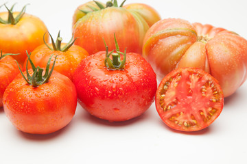 Conjunto de tomates maduros y medio tomate abierto por la mitad.