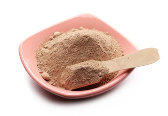 Pile powder, milled chocolate in bowl with wooden spoon isolated on white