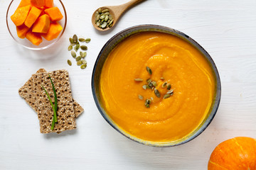 Pumpkin soup with seeds in a bowl, top view