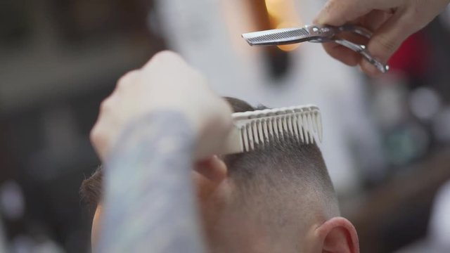 The wizard cuts a man, shaves his temples and neck.Scissors cut the head of a guy in a men's hair salon. Male hairdresser, grooming men. Haircut and haircut. The client at the hairdresser looks in the