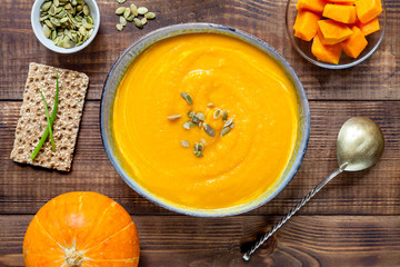 Pumpkin soup with seeds on wood table.
