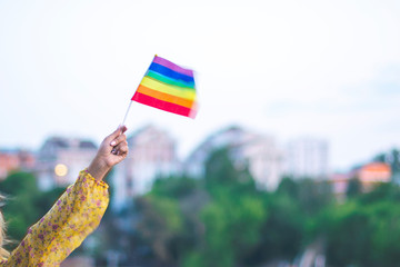 Girl's hand in dress holding multi-colored LGBT flag