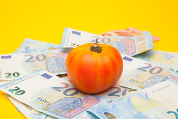 Tomate sobre un nido de billetes, tomate encima de dinero de curso legal. Bonito y saludable tomate...