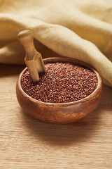 red quinoa in wooden bowl with spatula near beige napkin