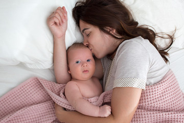 Fototapeta na wymiar A brunette woman kisses a baby. Mom with baby closeup