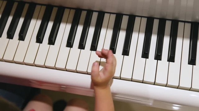 Closeup top view of little baby trying to play piano. Real time full hd video footage.