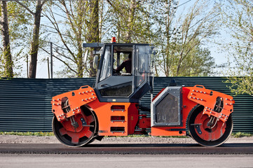 Asphalt paving machine. Road roller working on the new road construction site. Side view