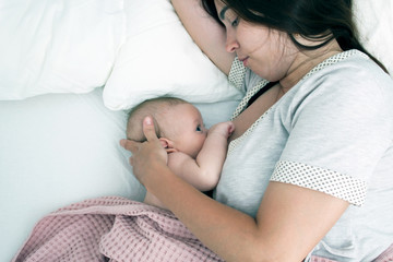 Brunette woman breastfeeds a baby. Mom with baby closeup