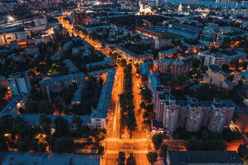 Night city panorama from above, aerial view of city after sunset with illuminated roads and traffic, buildings, drone photo
