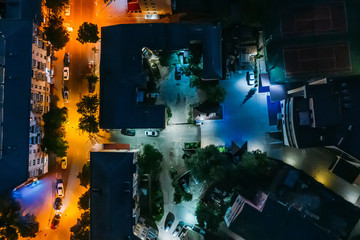Top down view of night city buildings, yards and streets, aerial shot