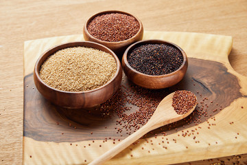 white, black and red quinoa in wooden bowls near spoon