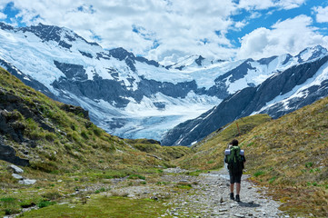 Fototapeta na wymiar Guy hiking through the valley towards a glacier and mountain range.