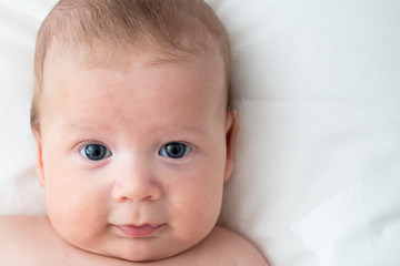 Happy baby lying on the bed. Baby on a white background close-up