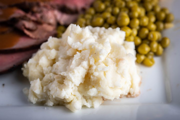 mashed potato serving with gravy sauce on roasted beef platter