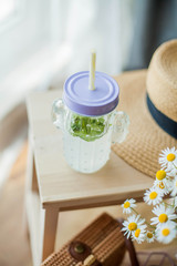Little wicker women bag, a bouquet of daisies, lemonade with mint, wicker hat, wooden chair. Spring. Cozy.