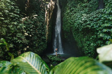 Woman in bikini enjoying waterfall in jungle. Woman enjoyingwaterfall in Bali. Slim body and black swimsuit, fashion model