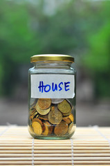 Coins in bottle with label House - financial concept